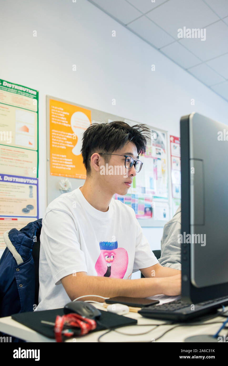 A computer technology class with students working and helping each