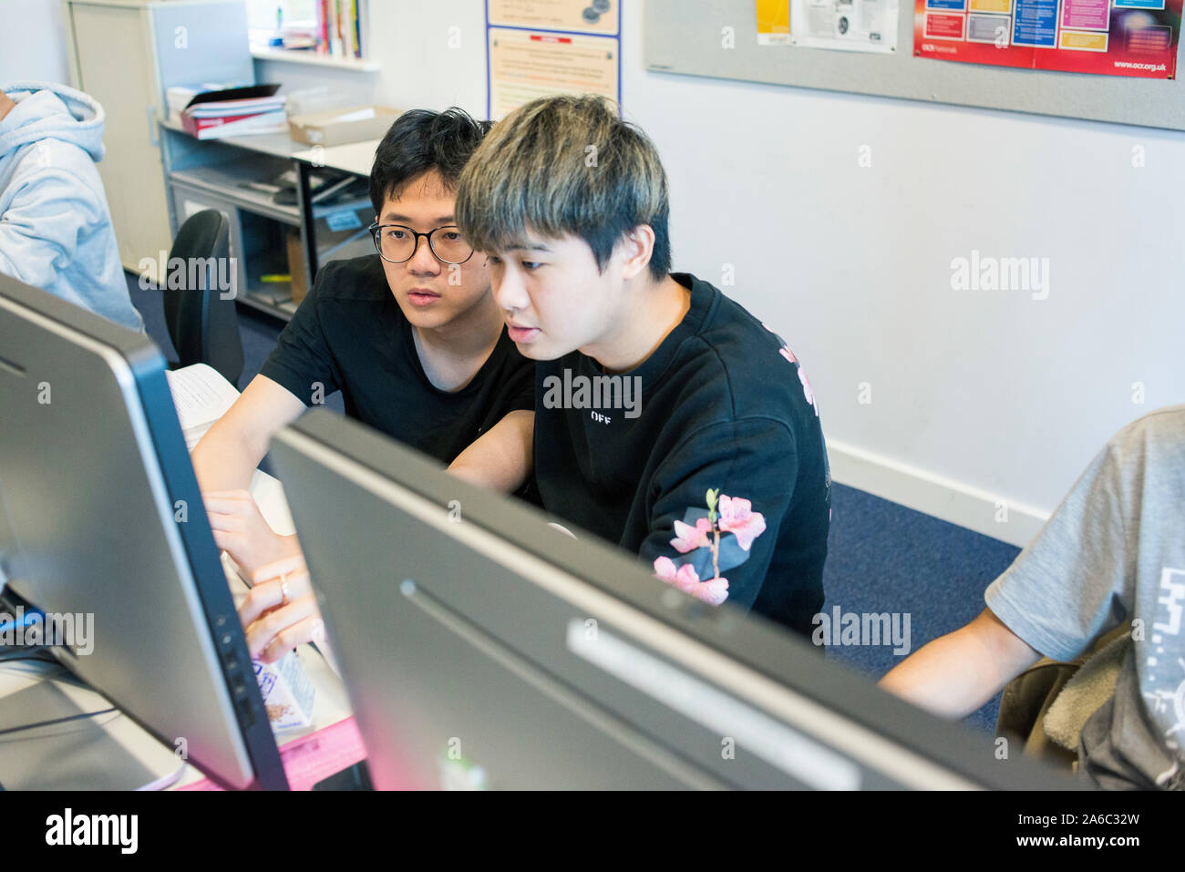 A computer technology class with students working and helping each