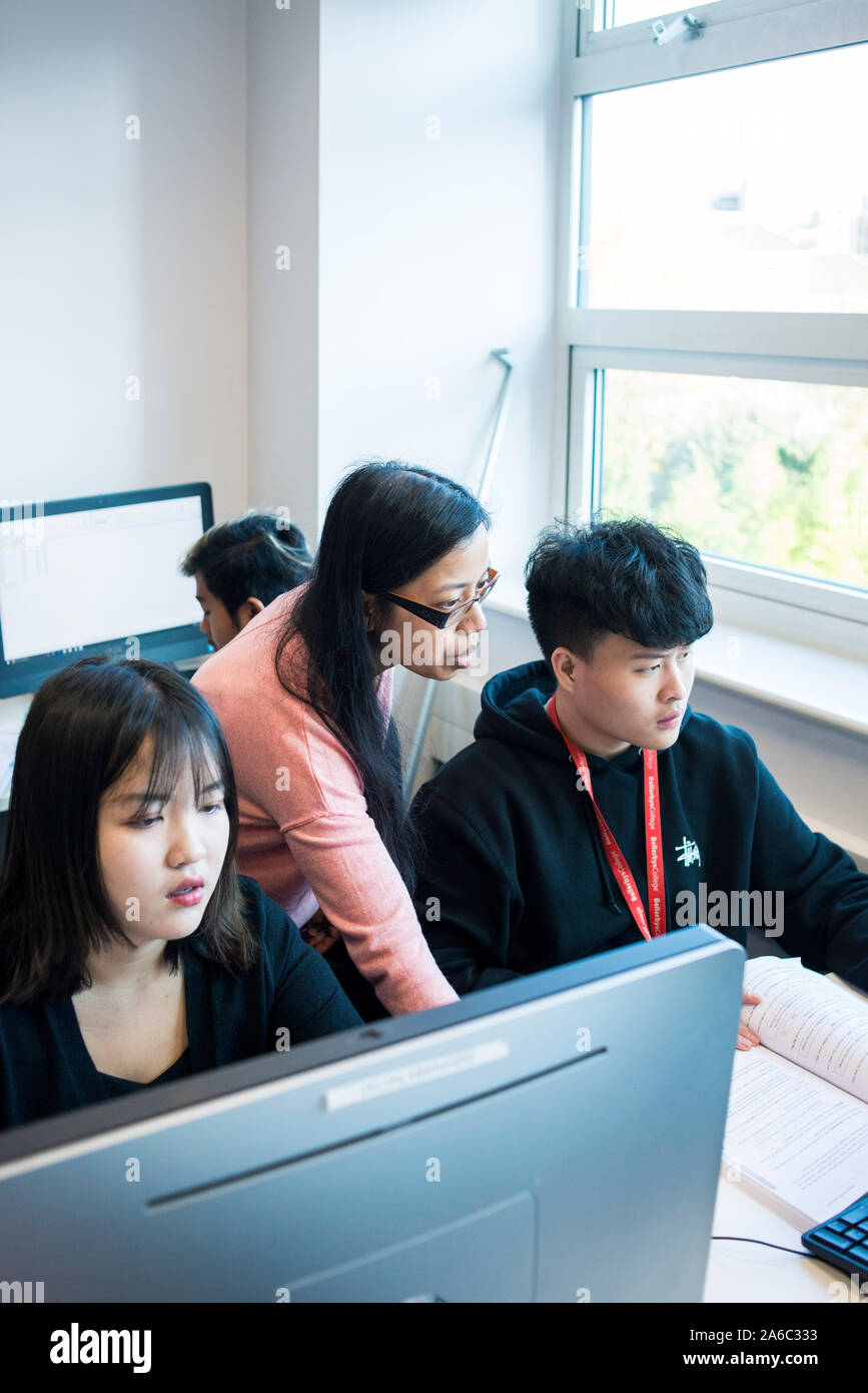 A computer technology class with students working and helping each