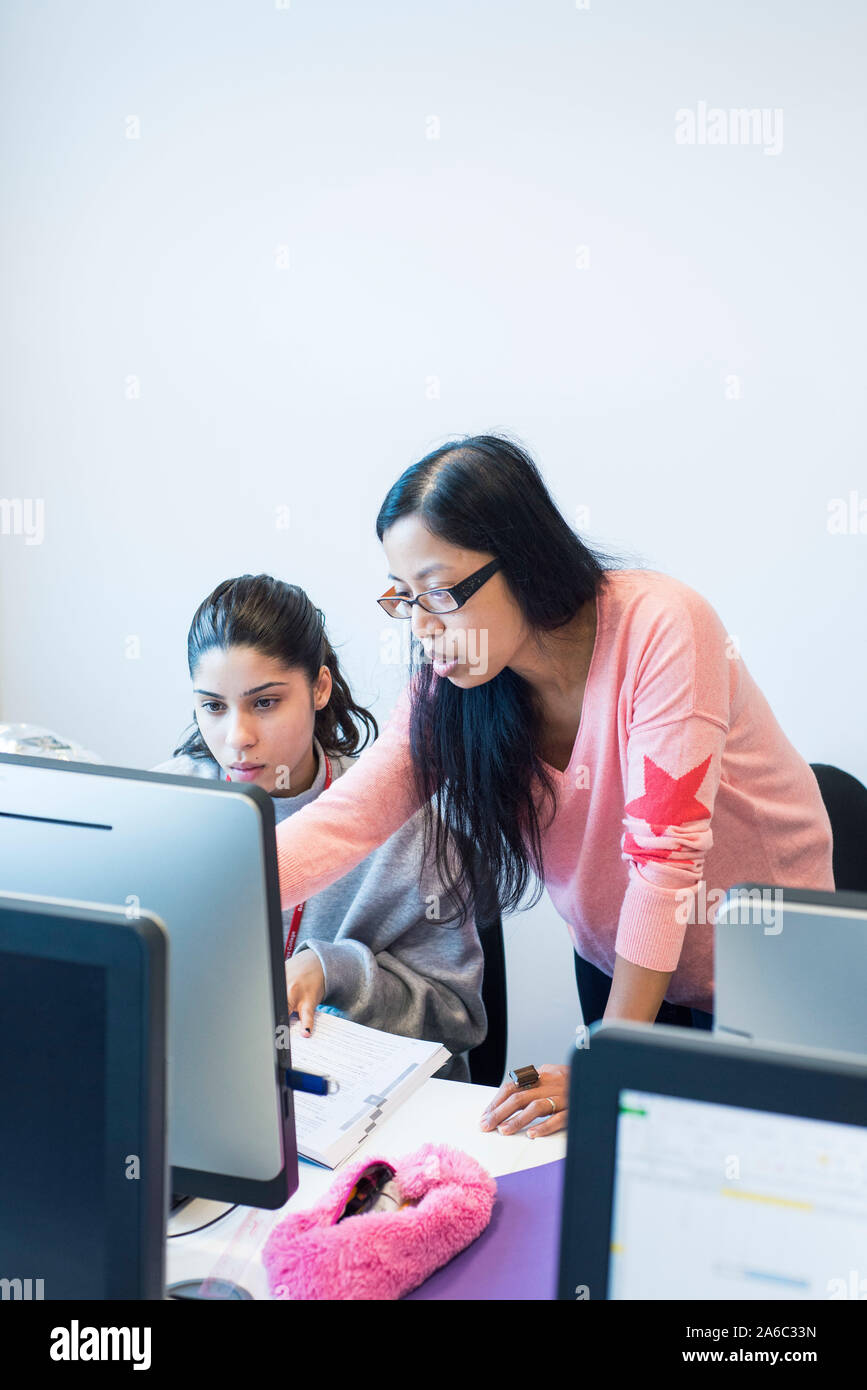 A computer technology class with students working and helping each