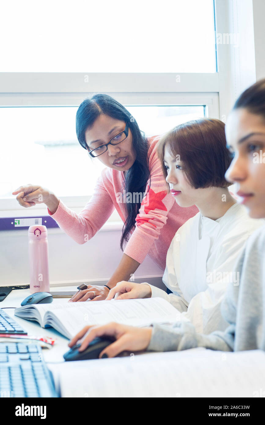 A computer technology class with students working and helping each