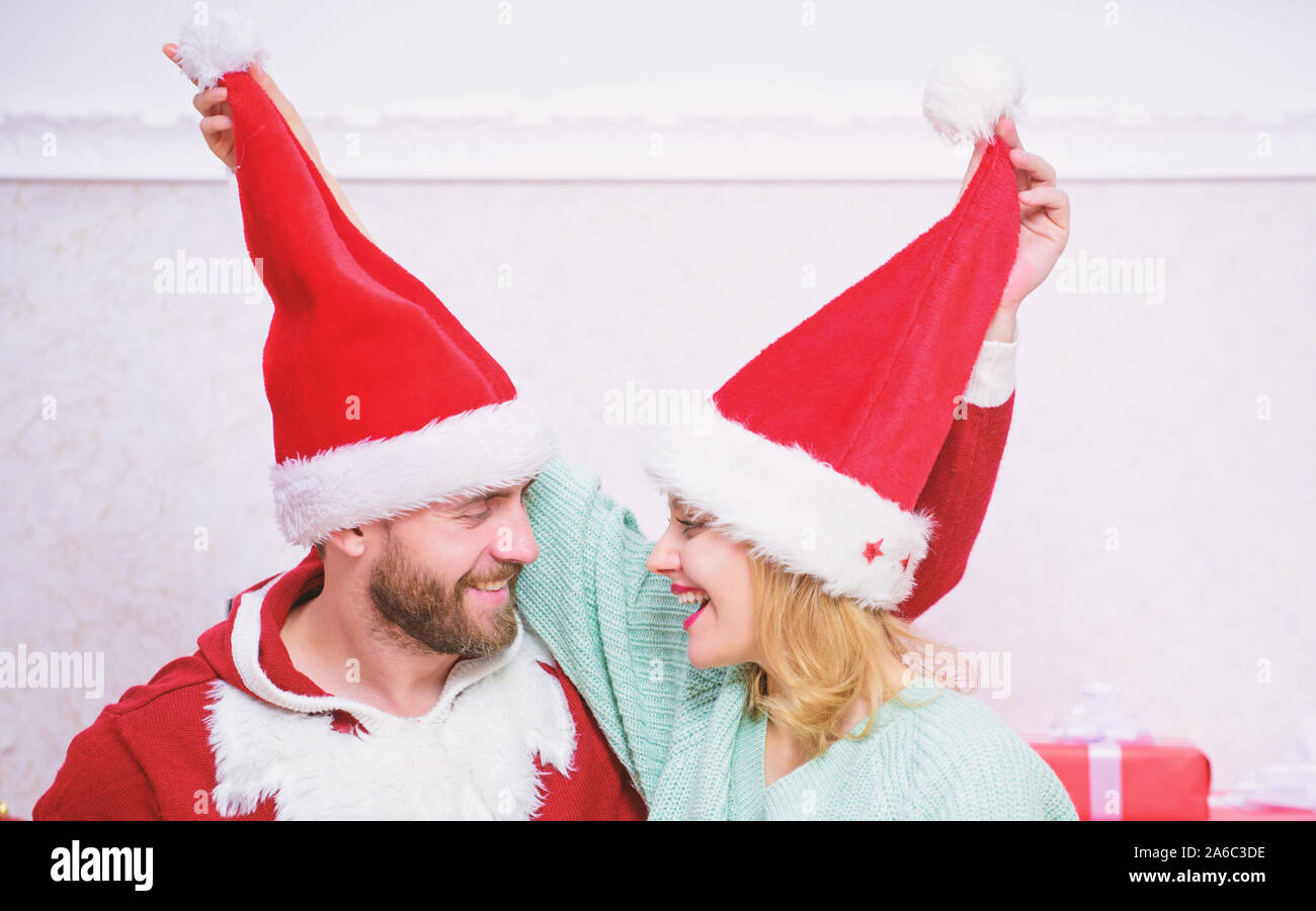 Couple wear hats as santa claus christmas tree background. It is easy to spread happiness around. Happy family celebrate christmas. Christmas fun concept. Couple in love enjoy christmas celebration. Stock Photo
