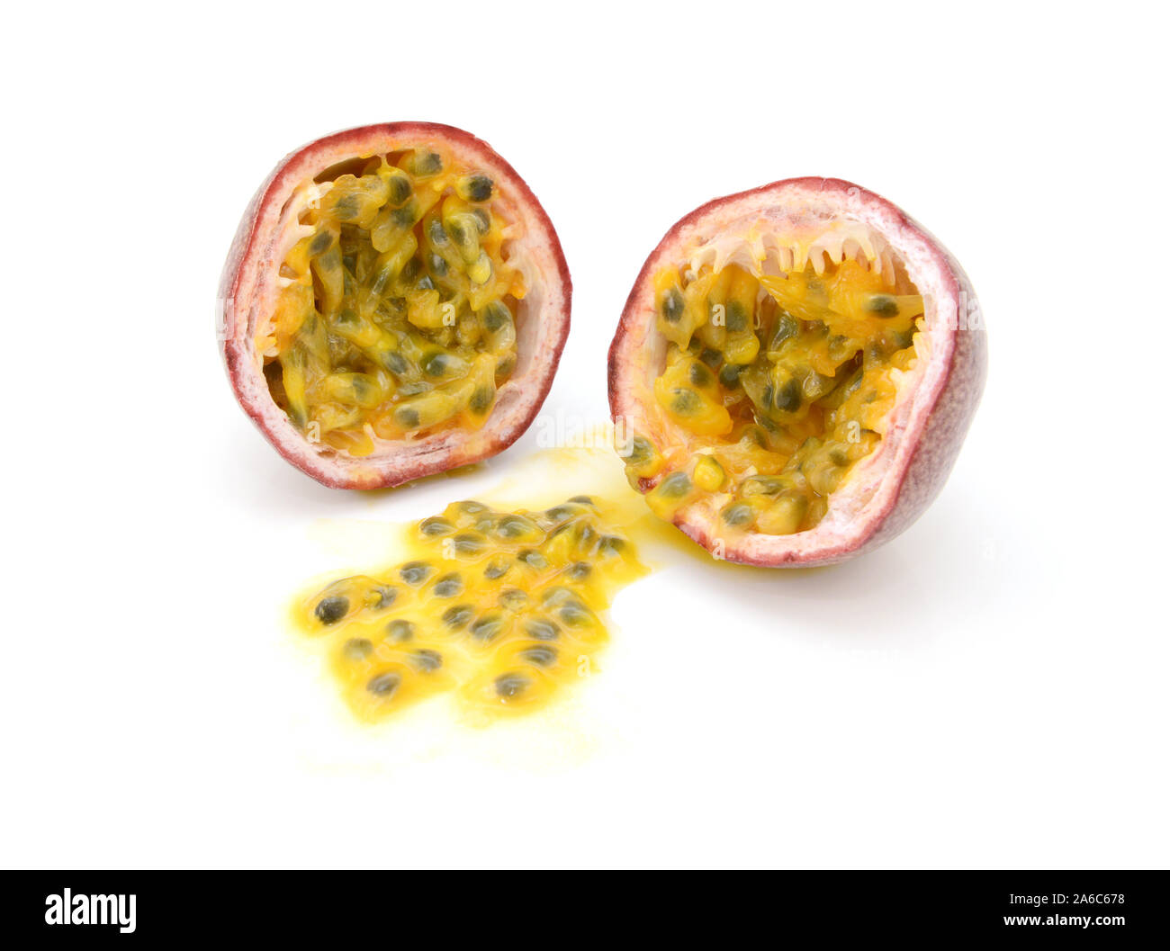 Passion fruit cut in half with juicy yellow pulp and seeds, on a white