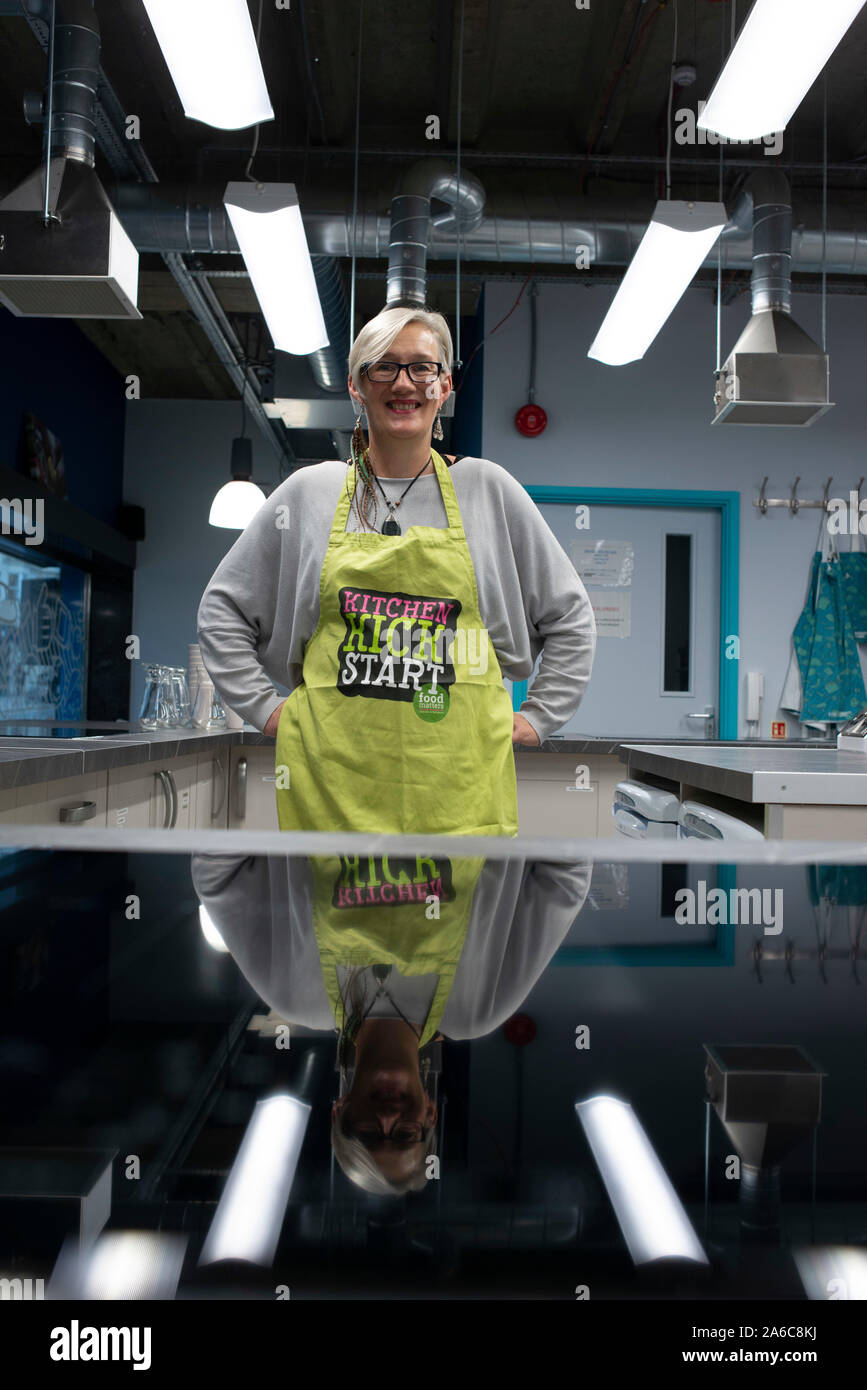 A chef stands in an industrial clean kitchen with an apron on. Stock Photo