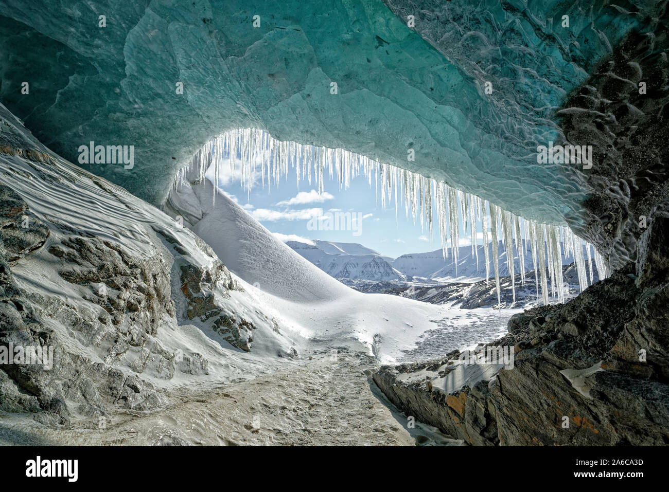 Looking through an opening in an ice cave of a glacier to the mountains of Svalbard. Nordenskjöldbreen, Spitsbergen, Svalbard, Norway Stock Photo