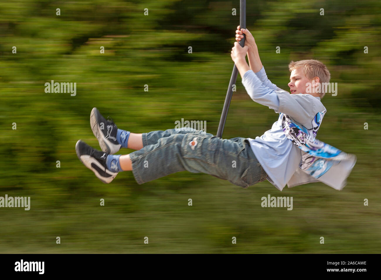 A teenage boy is riding on an aerial runway. Stock Photo