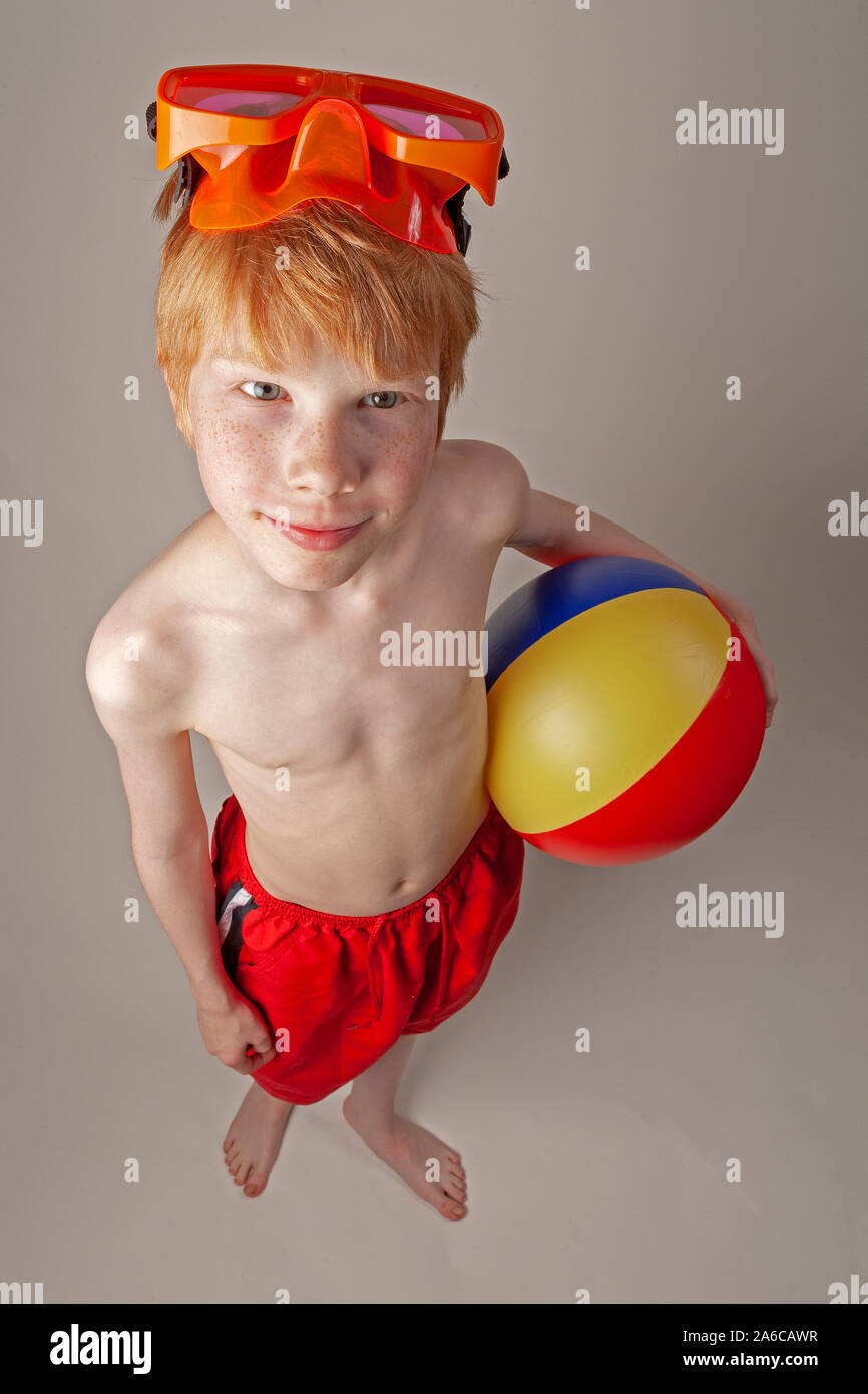 A young boy with divinggoggles and beach ball is ready for the summer