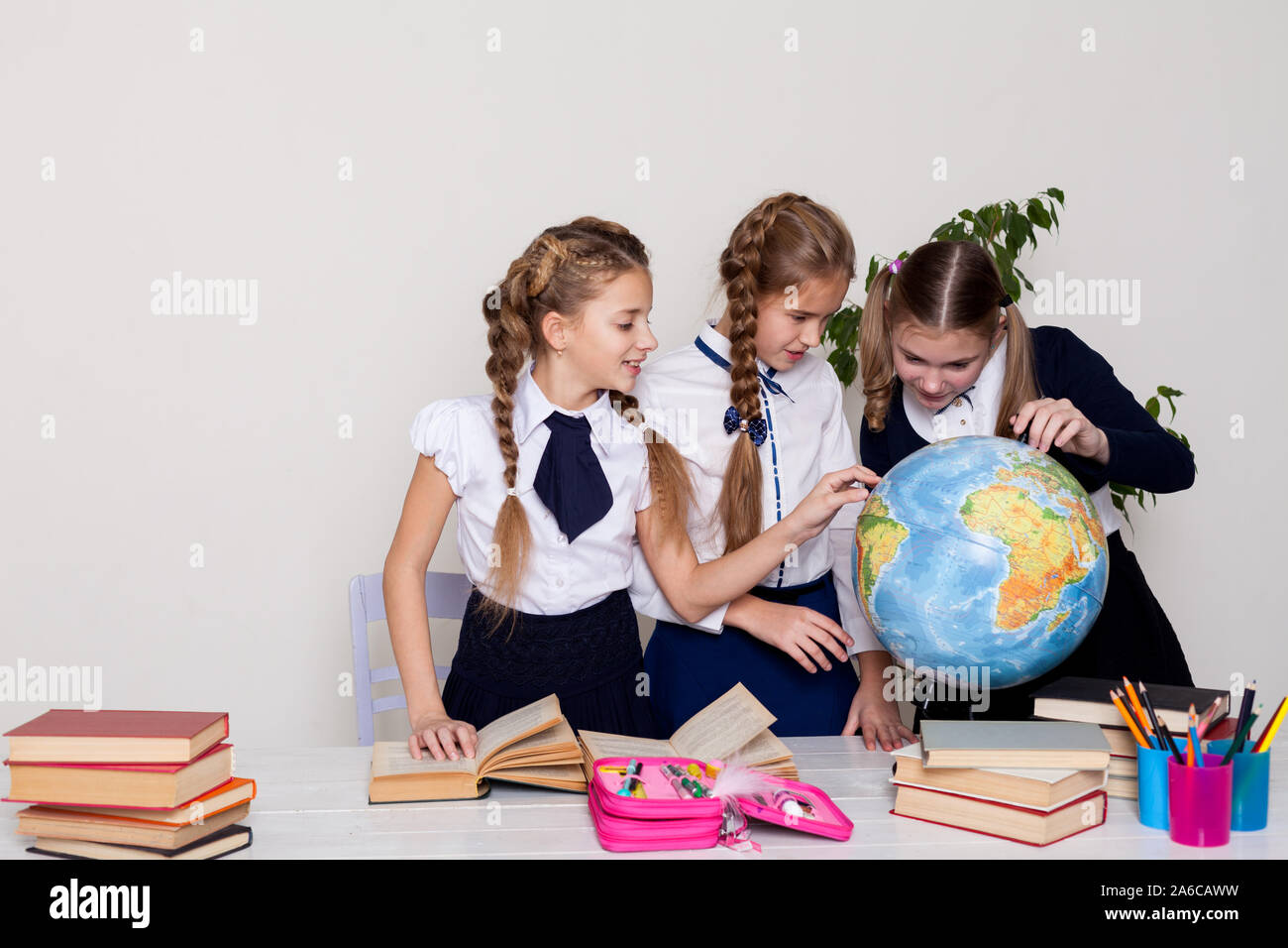 three girls watching the globe in geography class Stock Photo - Alamy