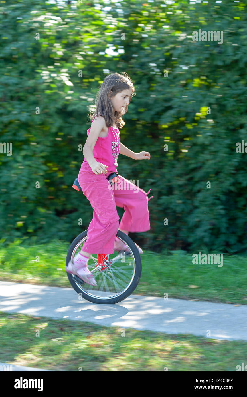 A young girl is riding a unicycle. Stock Photo