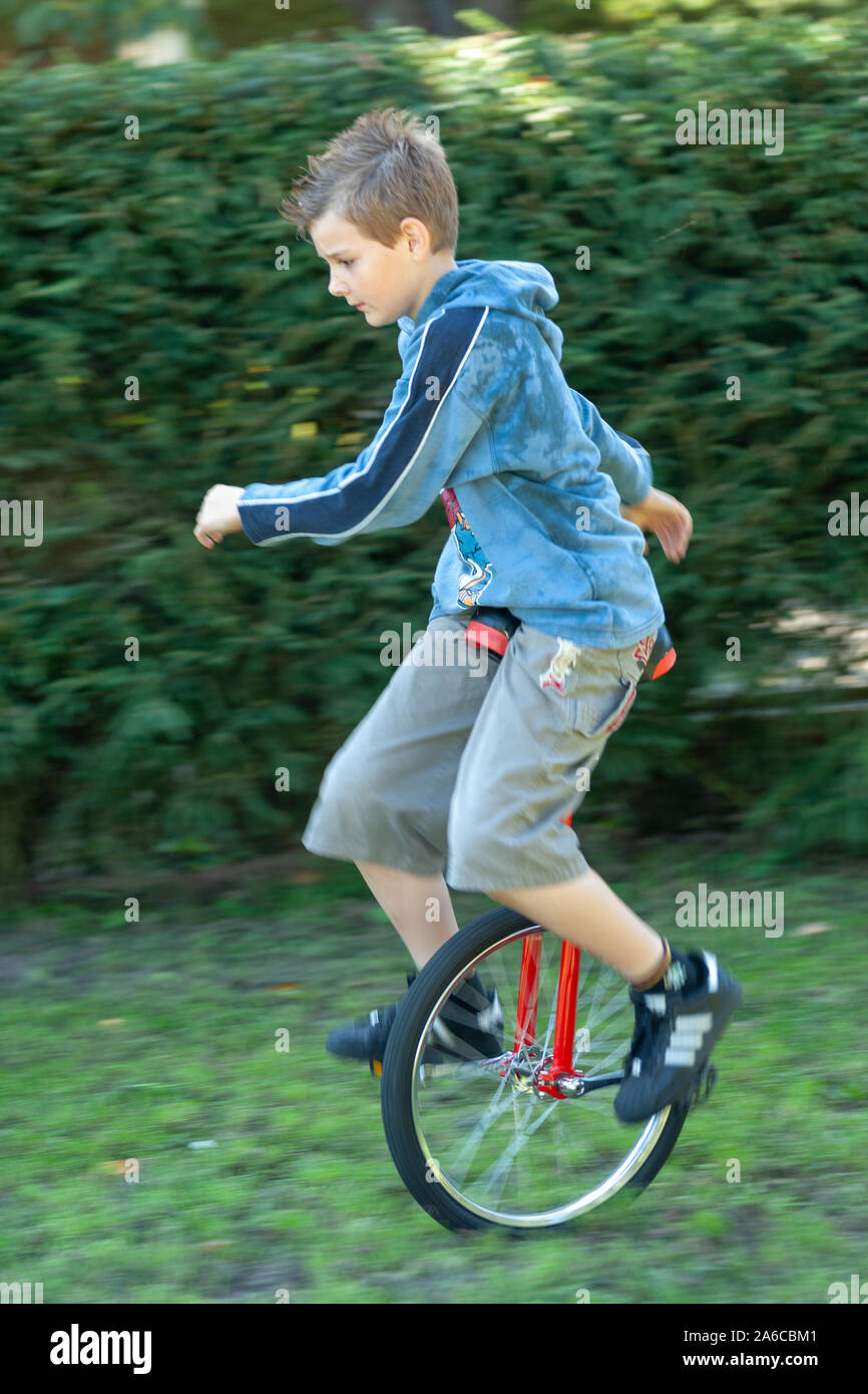 A young is boy riding a unicycle. Stock Photo