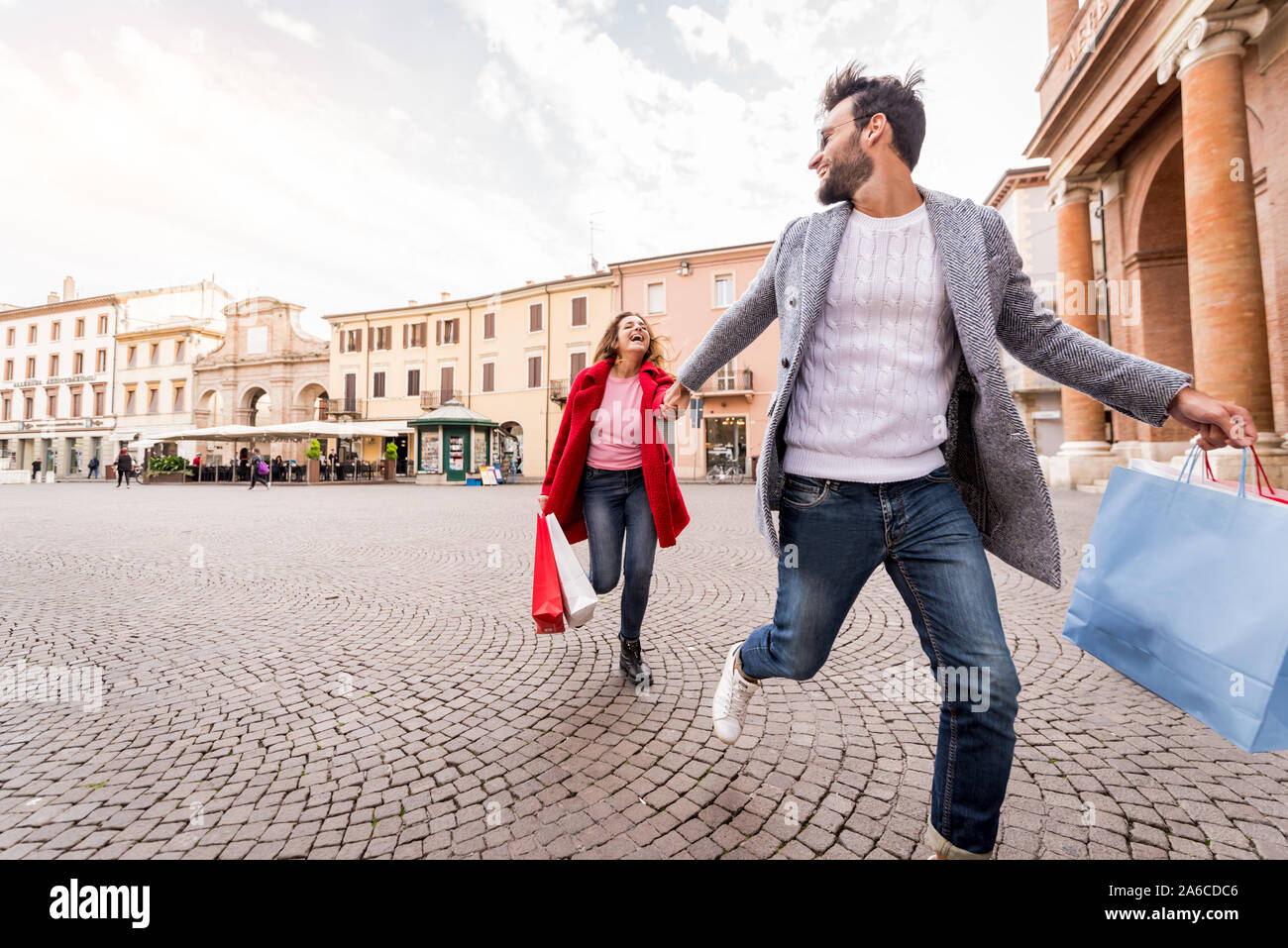 Young happy couple with shopping bags running in the city. Tourist walking in a city street Stock Photo