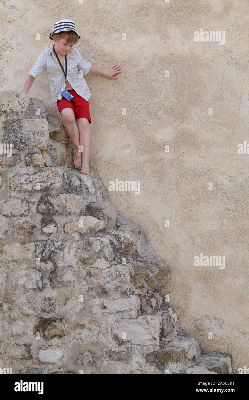 A little boy is carefully going down stone stairs, Croatia. Stock Photo