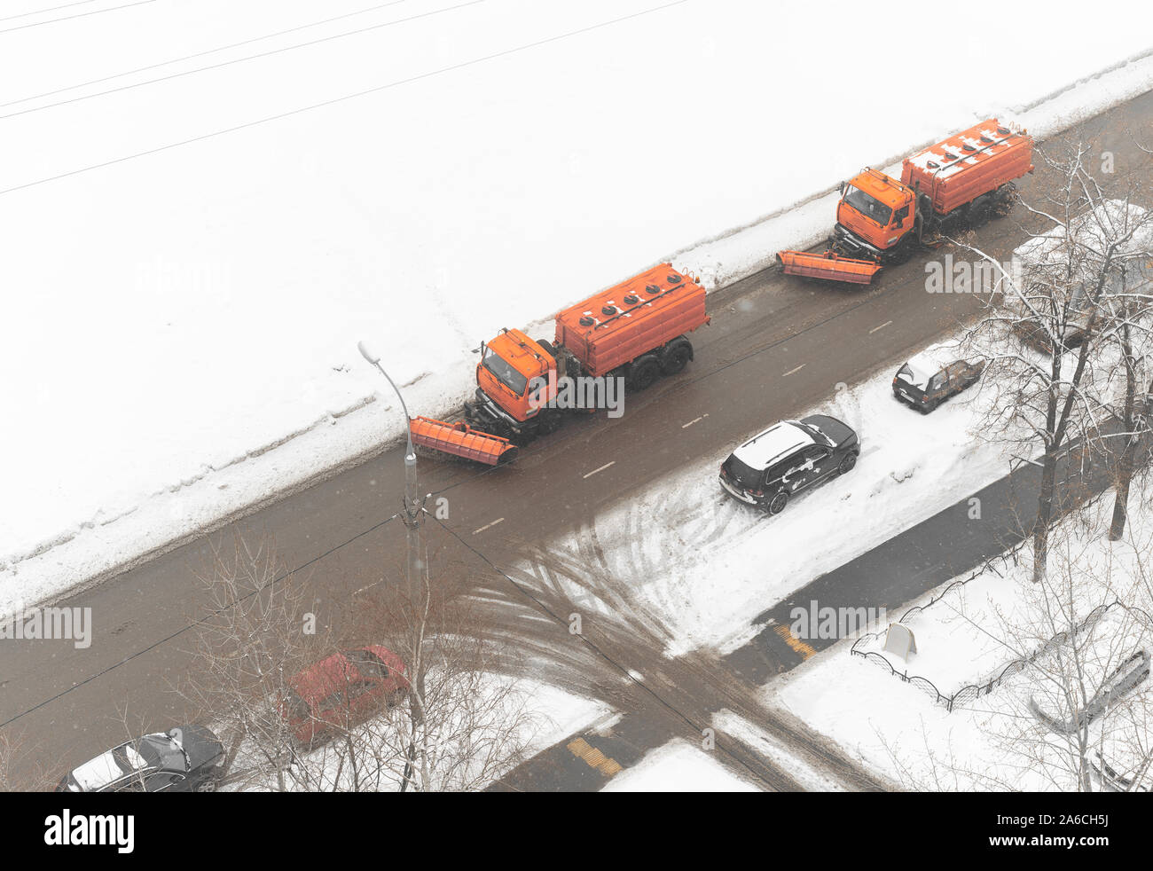 machines remove snow and spray chemicals on urban road Stock Photo
