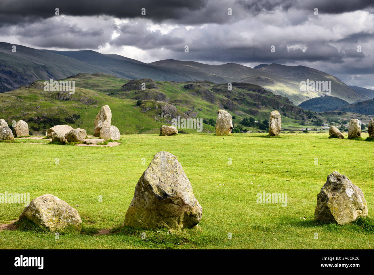 Castlerigg Stone Circle under dark storm clouds on summer solstice eve with Helvellyn Range mountains Keswick Cumbria England Stock Photo