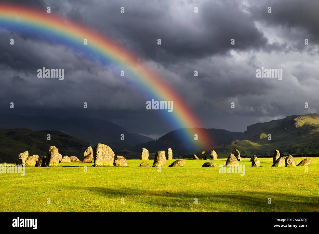 Rainbow over Castlerigg Stone Circle on summer solstice eve with sun and dark clouds in Cumbrian Mountains Lake District Keswick England Stock Photo