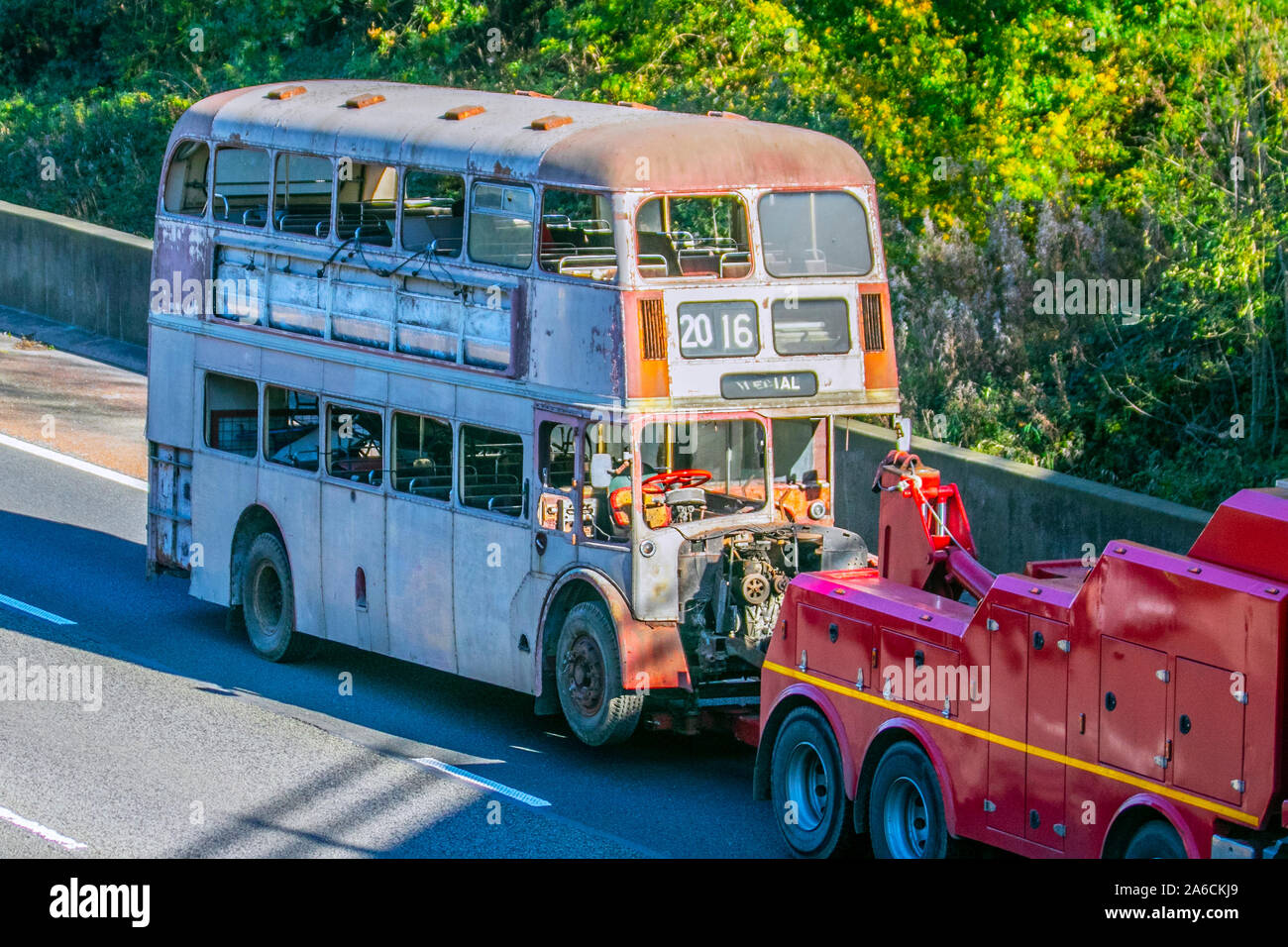 1950s-era automobiles barn garage find vehicle restoration project; Vintage bus towed on car trailer for restoration. UK Vehicular traffic derelict condition, rare collectible vintage classic transport, vintage, old buses, classics north-bound on the 3 lane M6 Motorway highway. Stock Photo