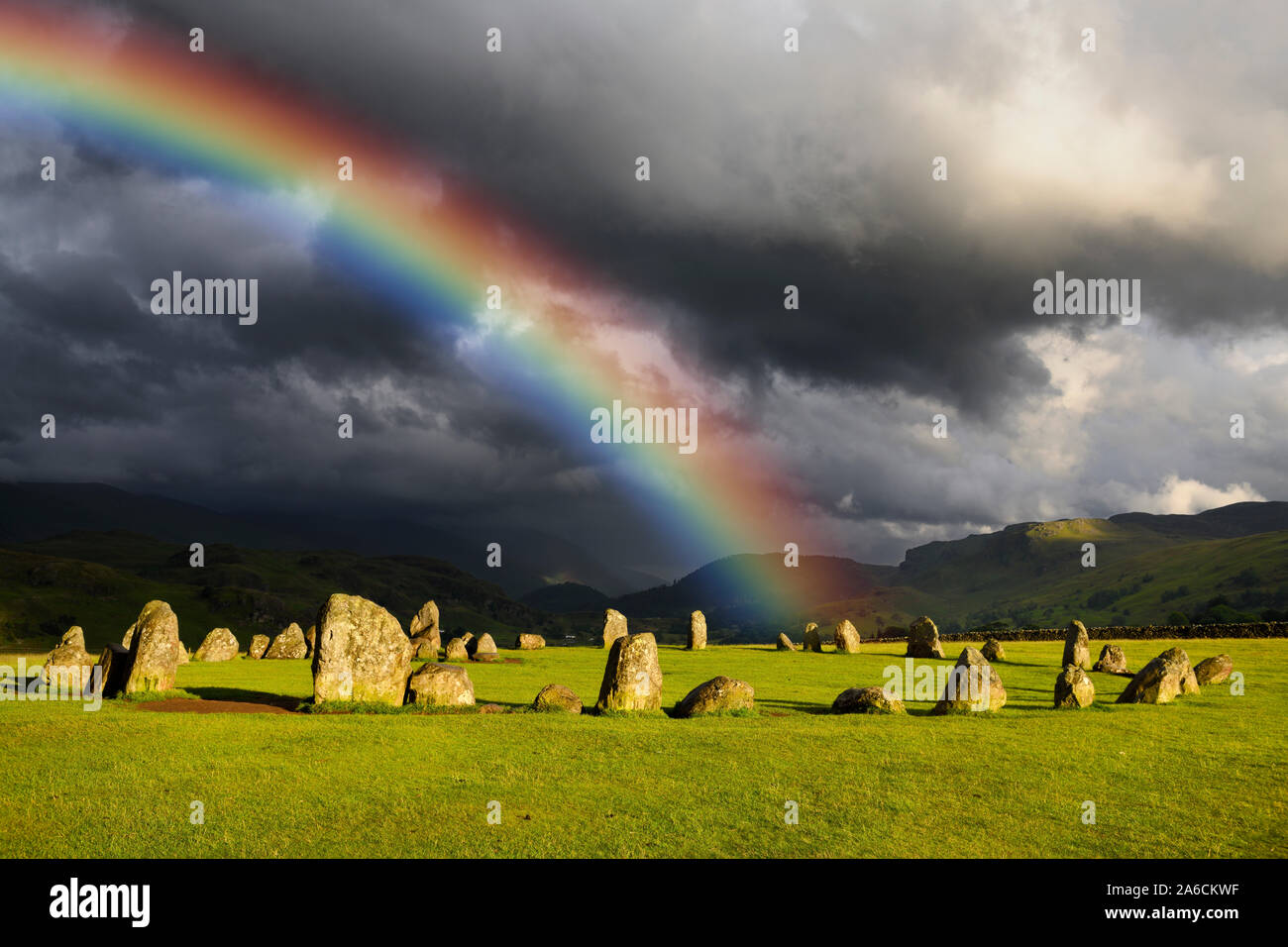 Rainbow over Castlerigg Stone Circle on summer solstice eve with sun and dark clouds over Cumbrian Mountains in Lake District Keswick England Stock Photo