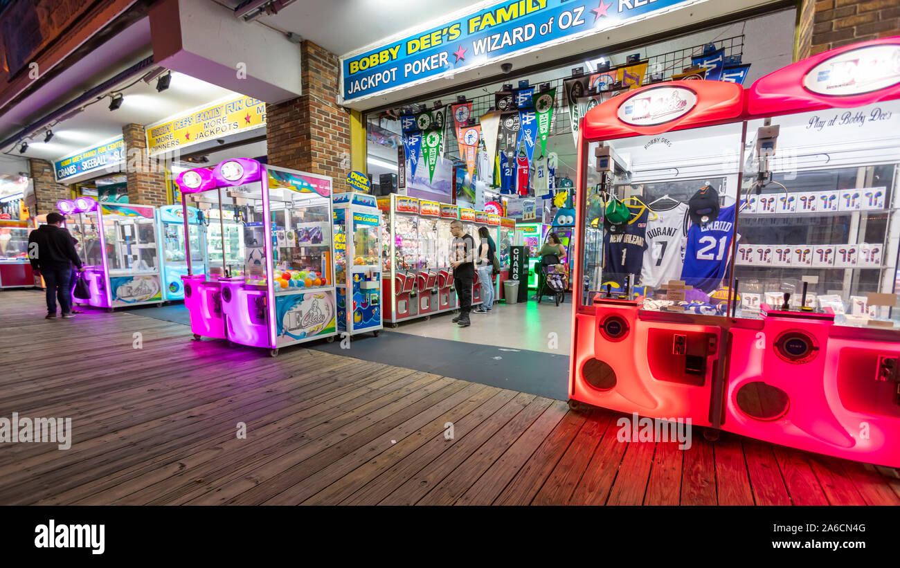 Few people walk and visit stores and game rooms on an empty boardwalk at night when summer is over. Stock Photo