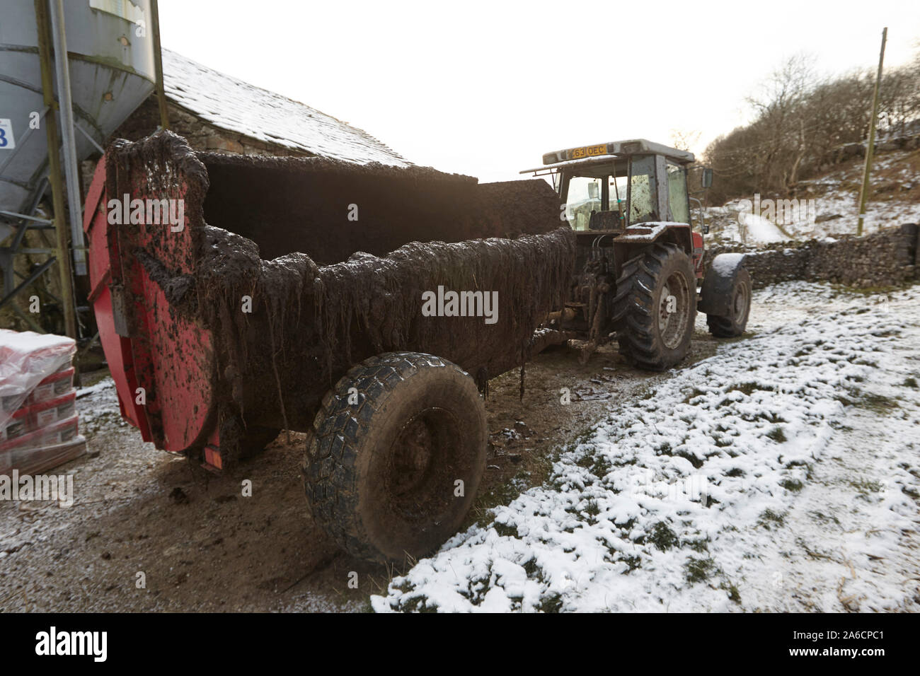 Tractor and muck spreader on Whernside carpeted in snow and ice mid winter Yorkshire Dales Stock Photo