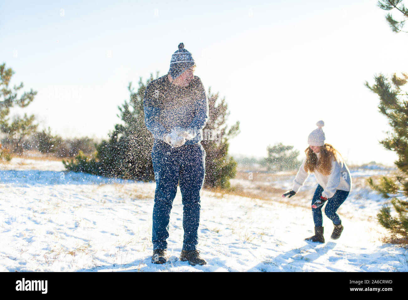 Loving couple play snowballs in winter in the forest. Throw each other ...
