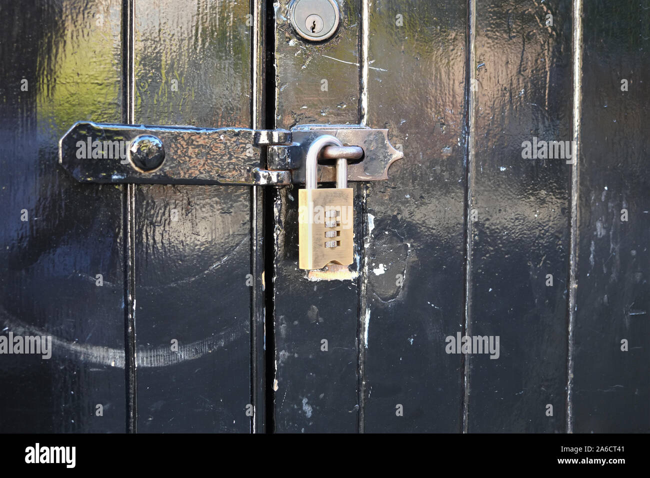 October 2015 - Brass padlock on hasp and staple lock to a black door Stock Photo