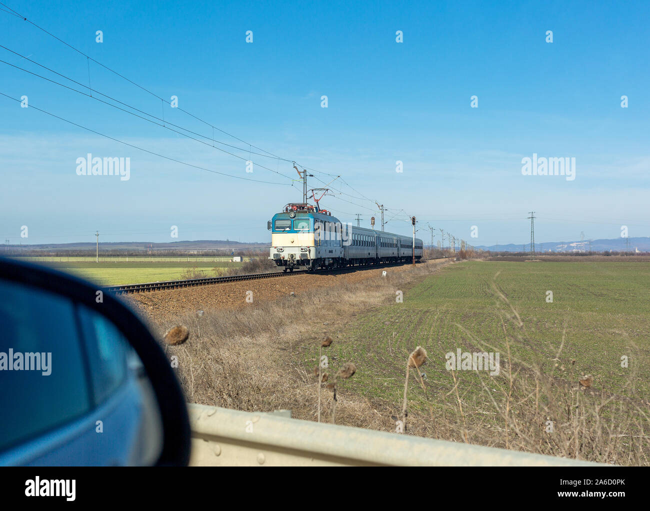 View of approaching train and part of side view mirror of car standing in front of level crossing Stock Photo