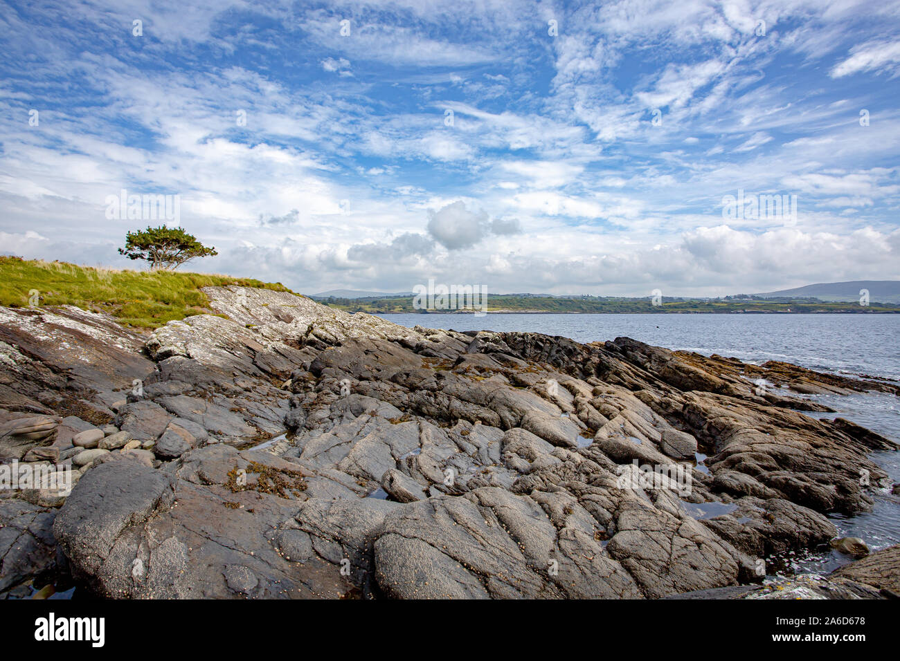 Dramatic landscape view at the coastline of Bantry Bay at the Eagle Point Campsite in Western Ireland. Blue sky with clouds. Stock Photo