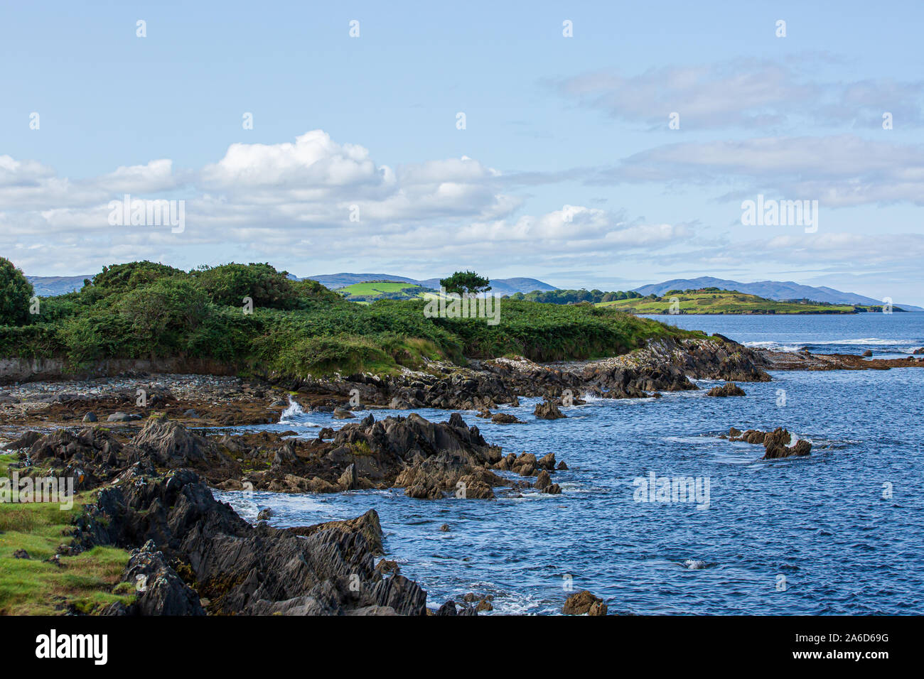 Dramatic landscape view at the coastline of Bantry Bay at the Eagle Point Campsite in Western Ireland. Blue sky with clouds. Stock Photo
