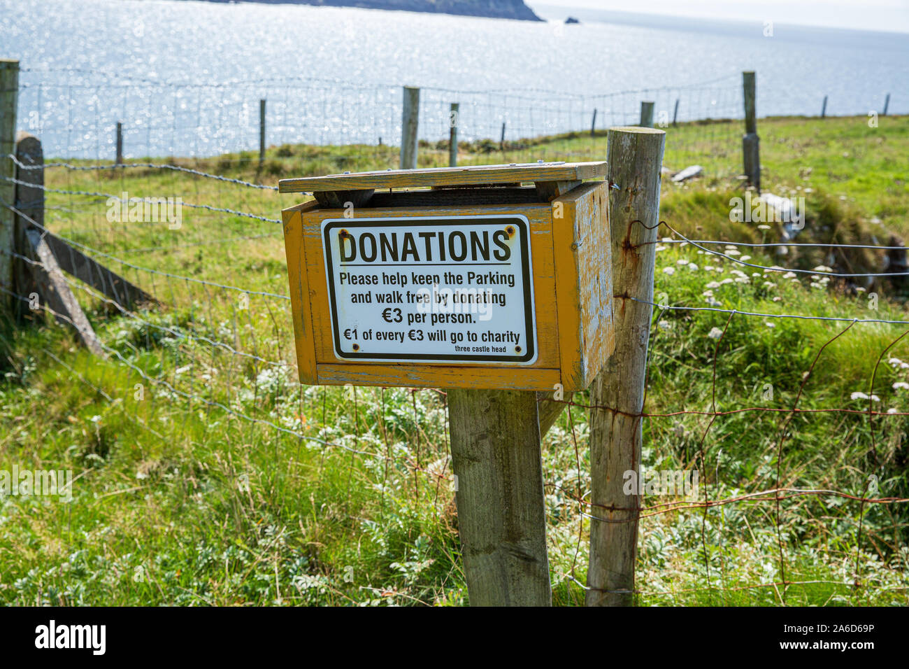 Yellow donation box at the start of a walking trail to the Thee Castle Head in Dunlough, Ireland Stock Photo