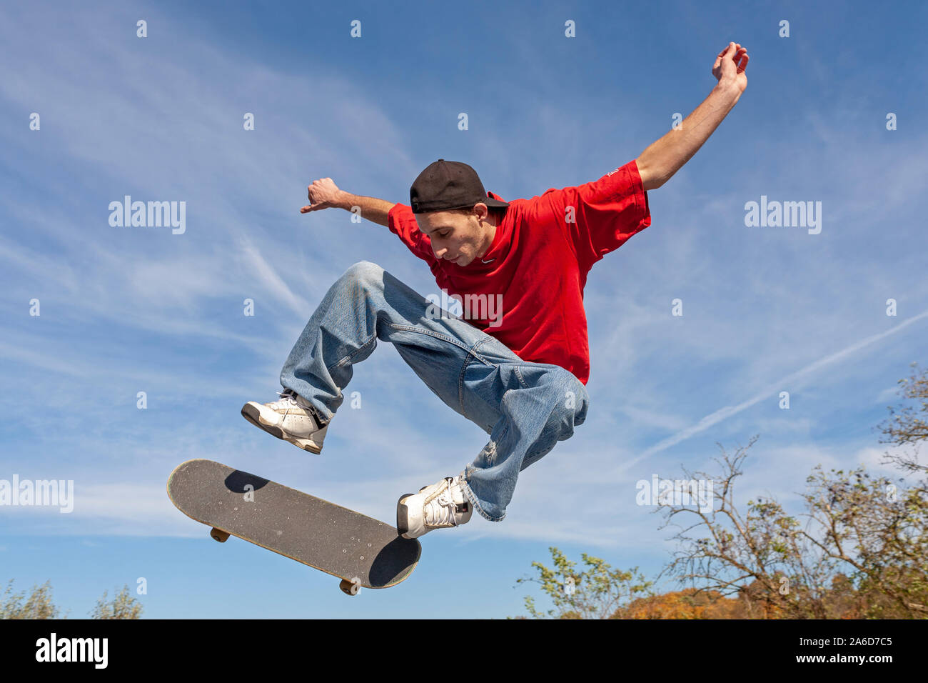A young man is jumping with his skateboard. Stock Photo