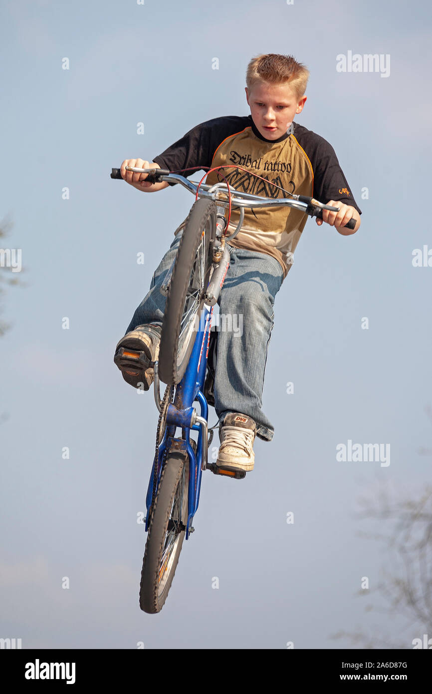 A jung boy is jumping with his bike Stoc