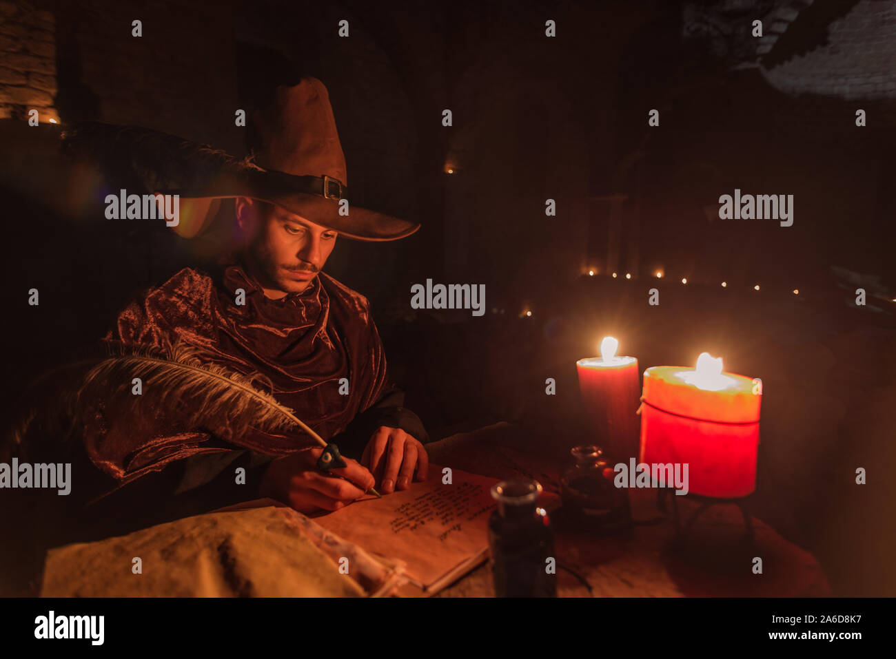 Young prophet Nostradamus writing his prophesies on a paper sitting in a ruined old church at night Stock Photo