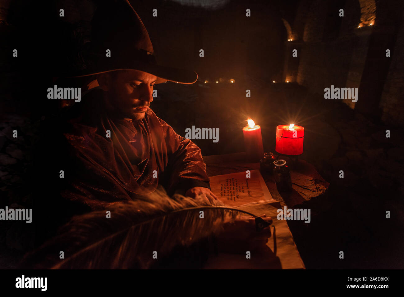 Young prophet Nostradamus writing his prophesies on a paper sitting in a ruined old church at night Stock Photo