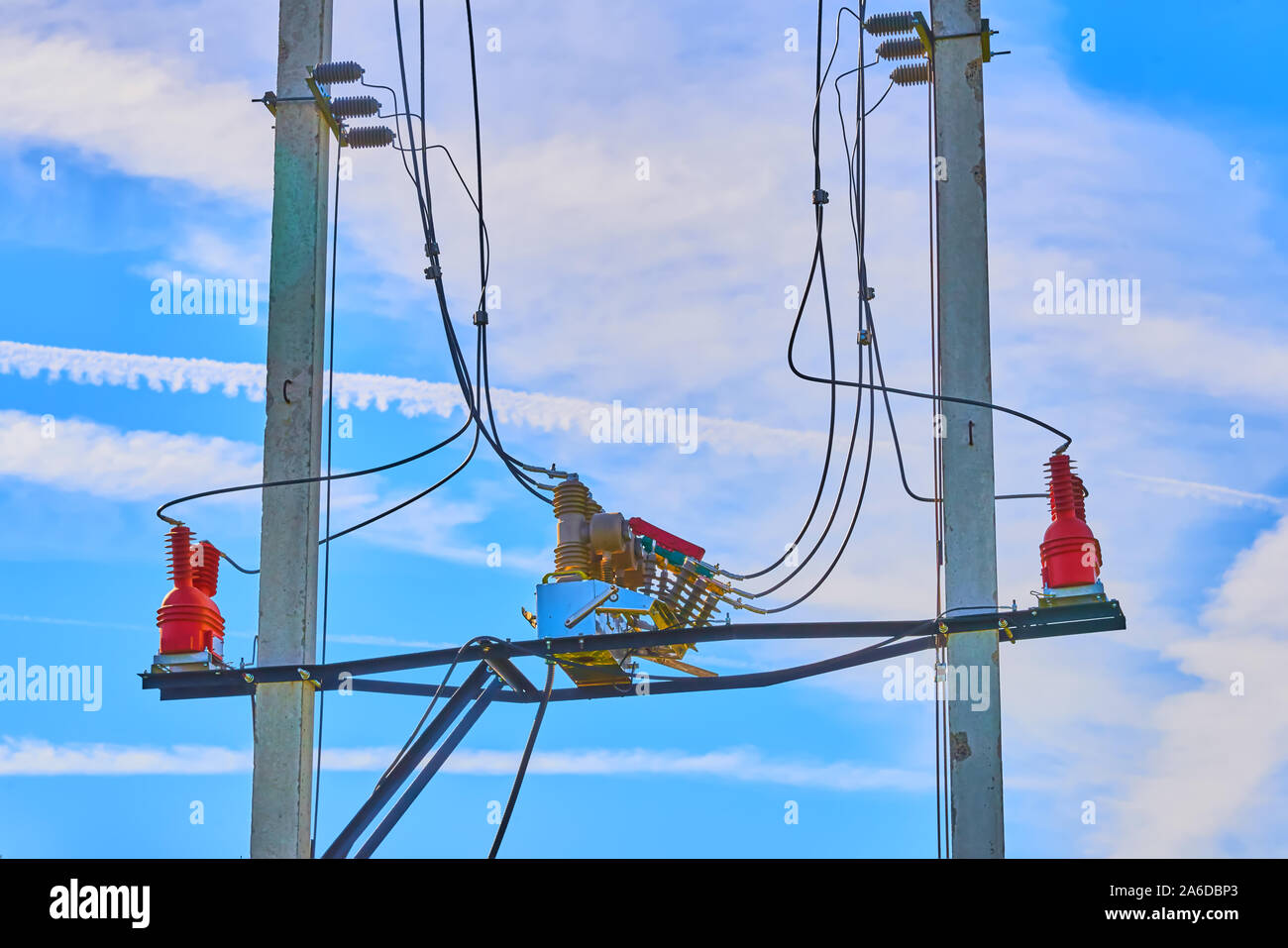 Electrical high voltage fuses on the grey concrete pillars with red isolators on the blue clear sky on the background Stock Photo