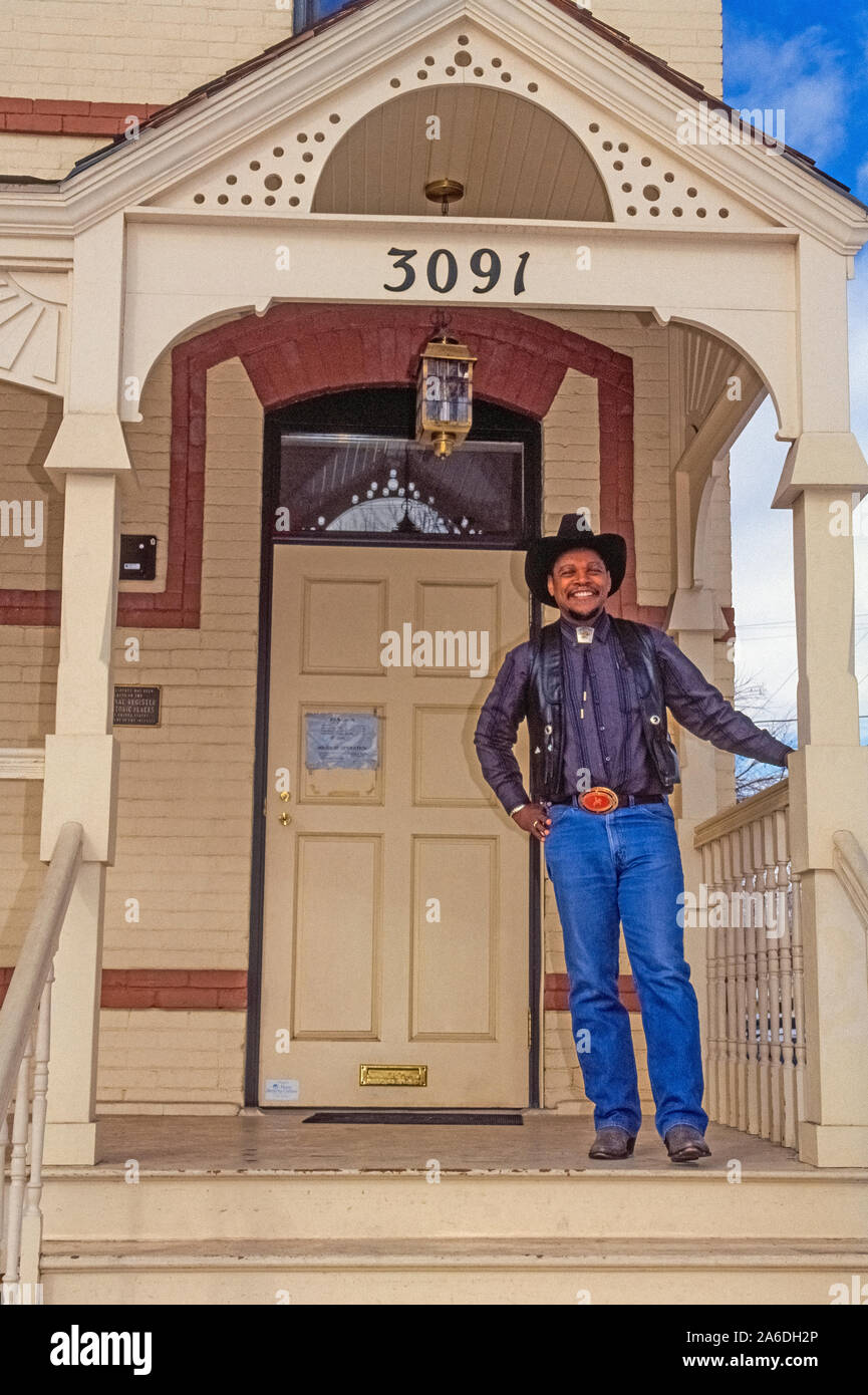 Paul Stewart poses with a smile on the front porch of the Black American West Museum & Heritage Center that he founded in Denver, Colorado, USA, to share his unique collection of stories and artifacts that portray the Western heritage of African Americans. Black cowboys of the early West are especially featured at the small museum located in an 1890s Victorian home at 3091 California Street.  A barber by trade, Stewart began exhibiting his collection in 1971 and continued until his death in 2015 at the age of 89. Historical photograph taken in 1990. Stock Photo
