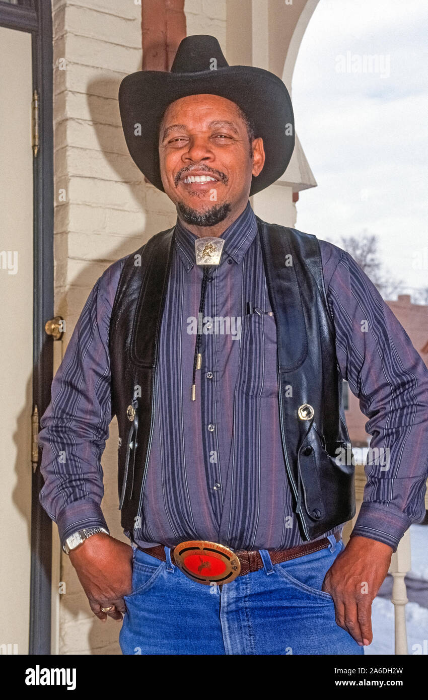 Paul Stewart poses with a smile on the front porch of the Black American West Museum & Heritage Center that he founded in Denver, Colorado, USA, to share his unique collection of stories and artifacts that portray the Western heritage of African Americans. Black cowboys of the early West are especially featured at the small museum located in an 1890s Victorian home at 3091 California Street.  A barber by trade, Stewart began exhibiting his collection in 1971 and continued until his death in 2015 at the age of 89. Historical photograph taken in 1990. Stock Photo