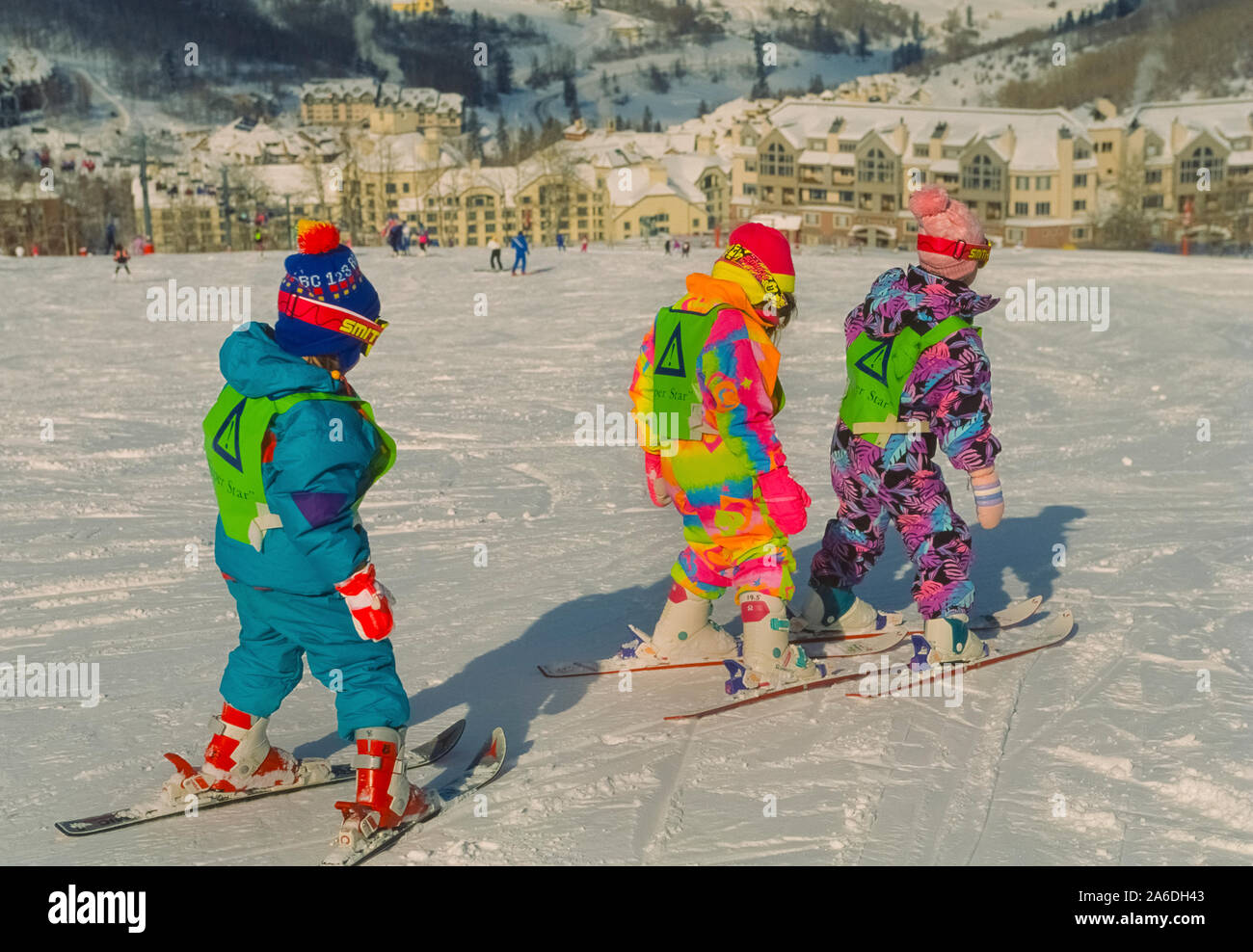 Three young first-time skiers follow one another on a snowy incline during a lesson at the Beaver Creek Ski School in the mountains of Colorado, USA. The skiing lessons at Beaver Creek Resort are designed for different ages, beginning with these three- to four-year-old children in their colorful snowsuits. Stock Photo