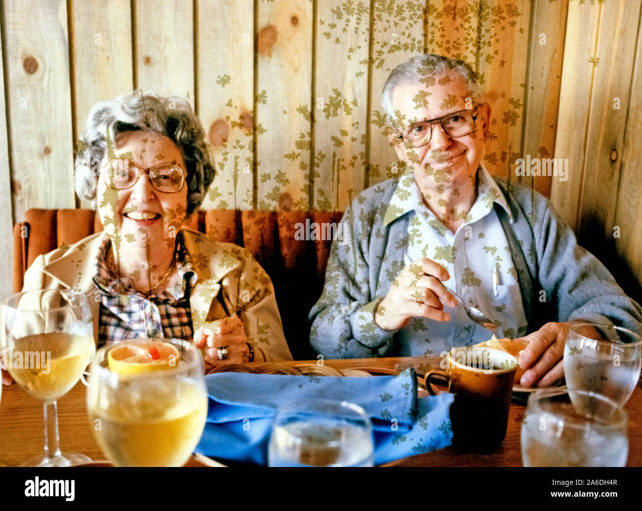 Irregular greenish spots caused by mold on a color film transparency have ruined this picture of an elderly American couple enjoying a meal  in a restaurant while on vacation in 1980. The cause of mold appearing on photographs over time is often a mystery. It frequently can be from excessive humidity or heat where the pictures have been stored. In regard to this image, the mold may have been caused by the leaching of chemicals from the plastic sleeve in which the Kodak Ektachrome 35mm slide was kept. Another possible cause for mold on photos is improper processing. Stock Photo
