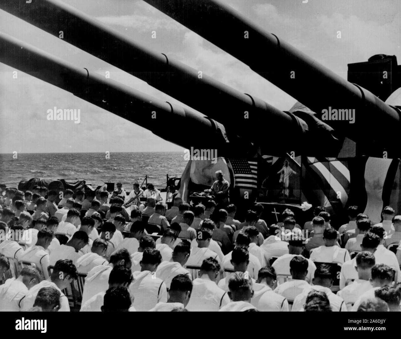 The crew of the USS SOUTH DAKOTA stands with bowed heads, while Chaplain N. D. Lindner reads the benediction held in honor of fellow shipmates killed in the air action off Guam on June 19, 1944 Stock Photo