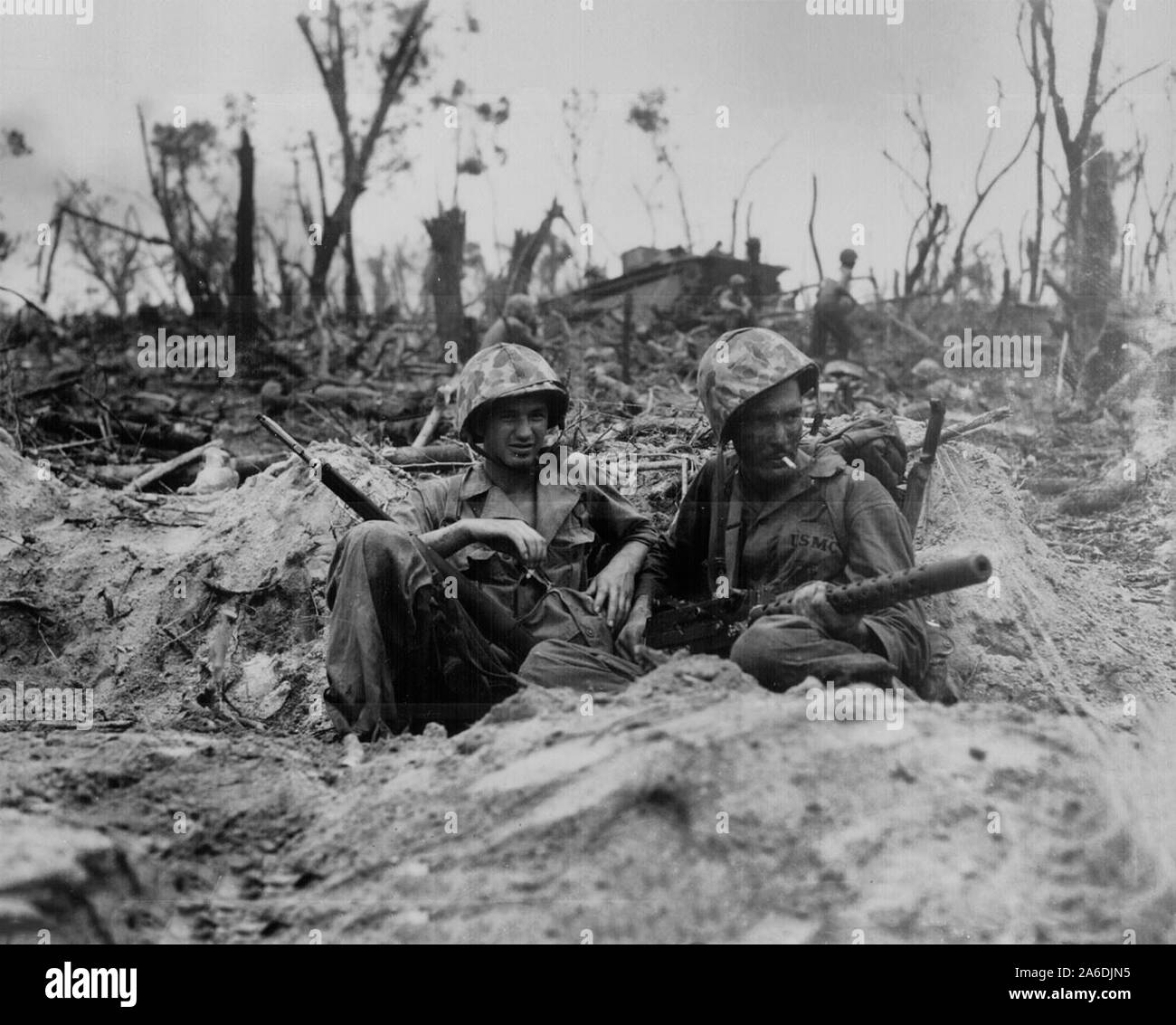 Marine Pfc. Douglas Lightheart (right) cradles his 30-caliber machine gun in his lap, while he and his buddy Pfc. Gerald Churchby take time out for a cigarette, while mopping up the enemy on Peleliu Island Stock Photo