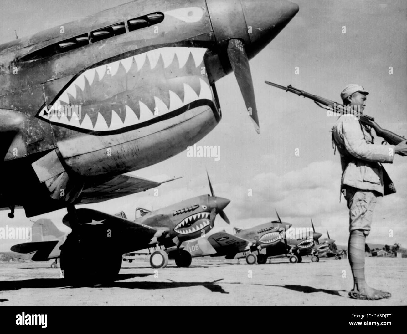 A Chinese soldier guards a line of American P-40 fighter planes, painted with the shark-face emblem of the 'Flying Tigers,' at a flying field somewhere in China, circa 1942 Stock Photo