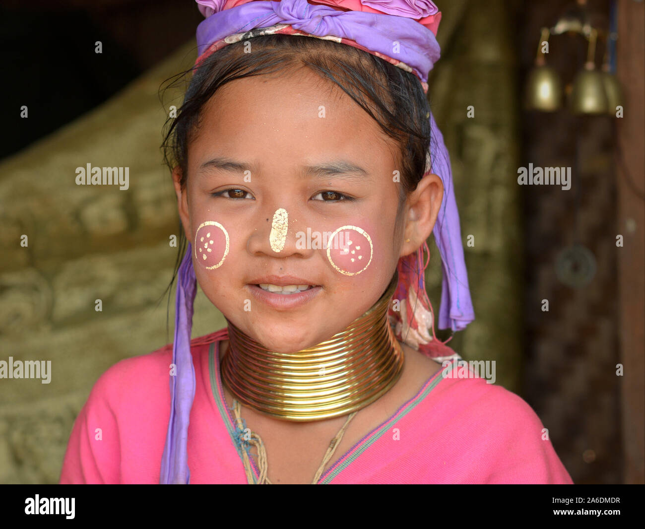 Pretty Myanmarese Kayan Lahwi longneck girl with Burmese thanaka face cosmetic and tribal Padaung brass neck rings/coils smiles for the camera. Stock Photo