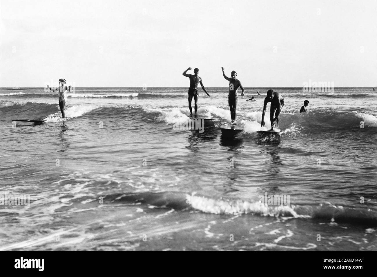 Vintage surfing photo from Waikiki Beach in Honolulu, Hawaii of surfers on wooden surfboards sharing a wave. Stock Photo