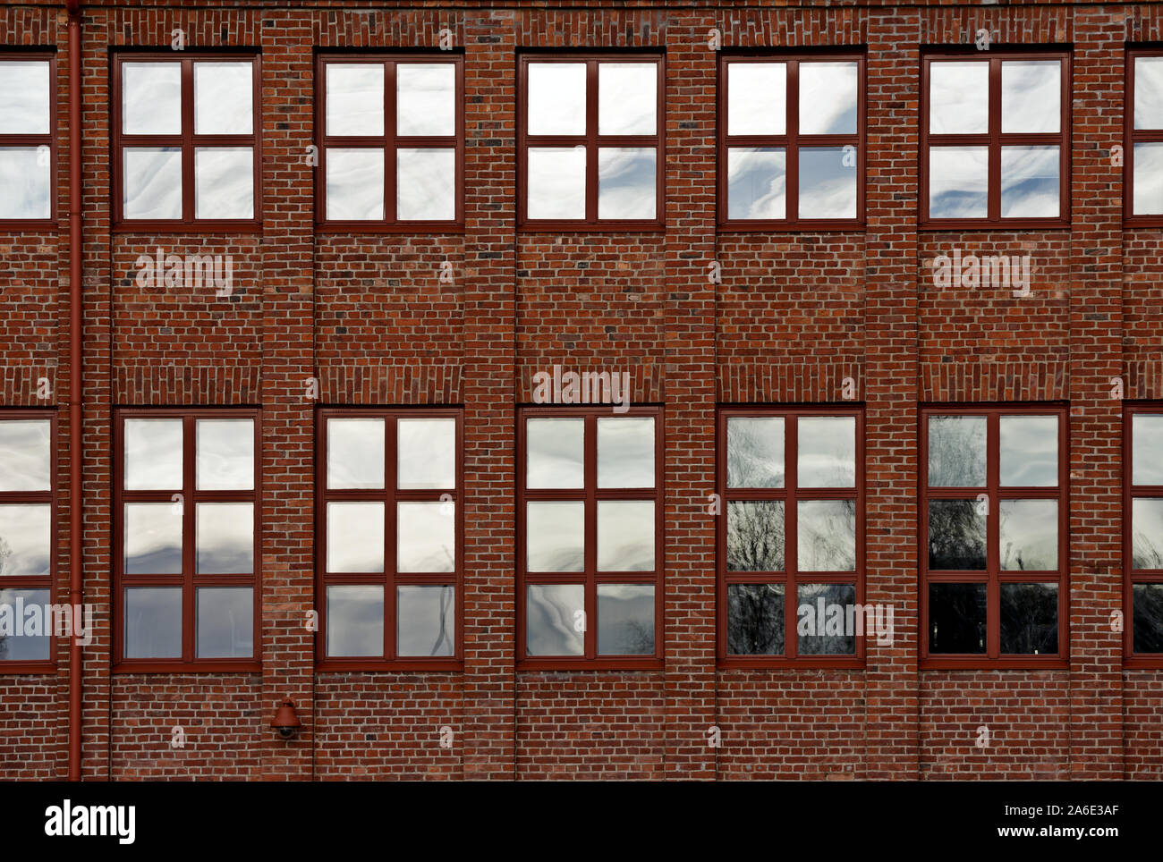 An old factory building with a lot of windows on the brick wall in daylight Stock Photo