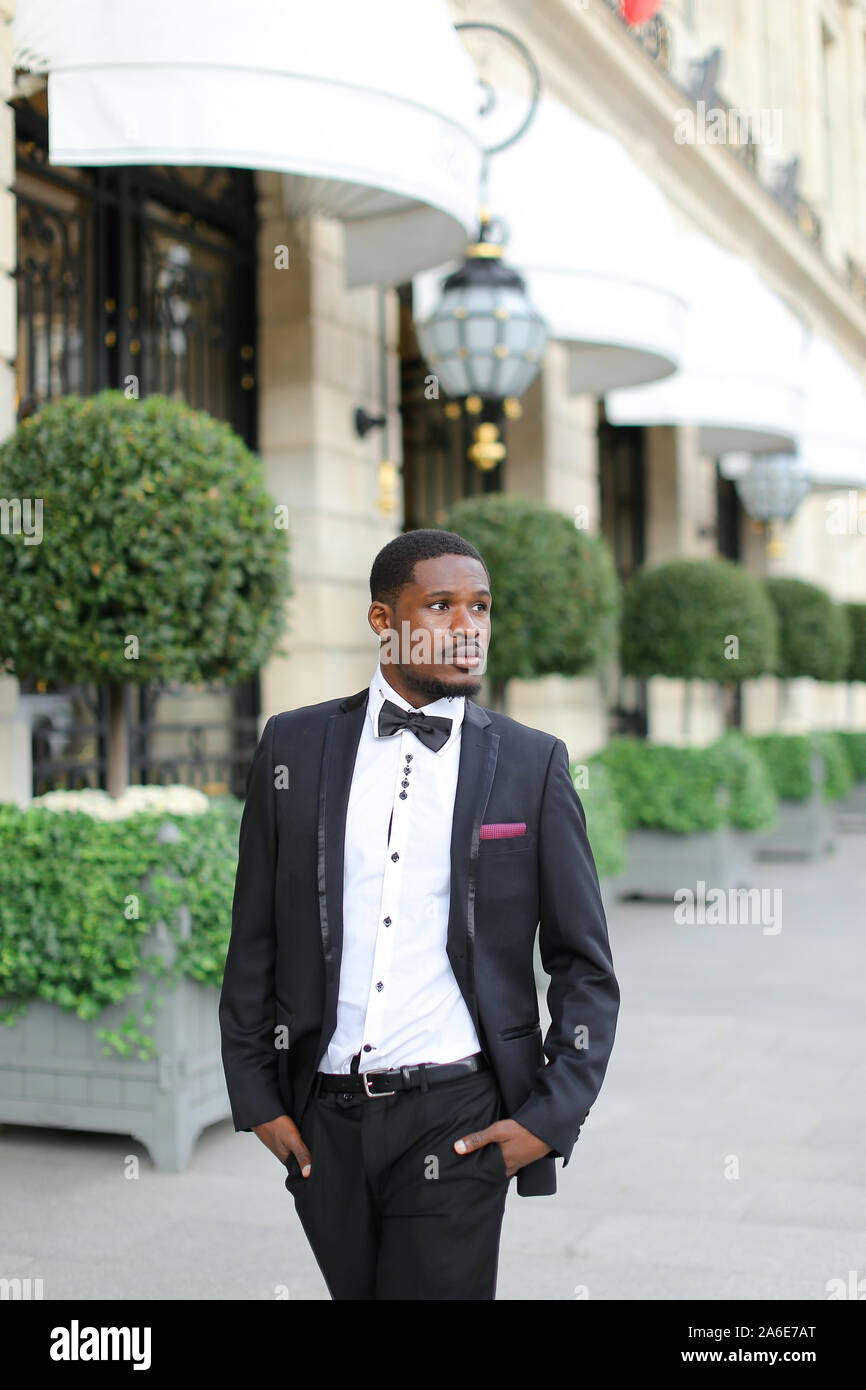 Afro handsome american man wearing suit and standing near building ...