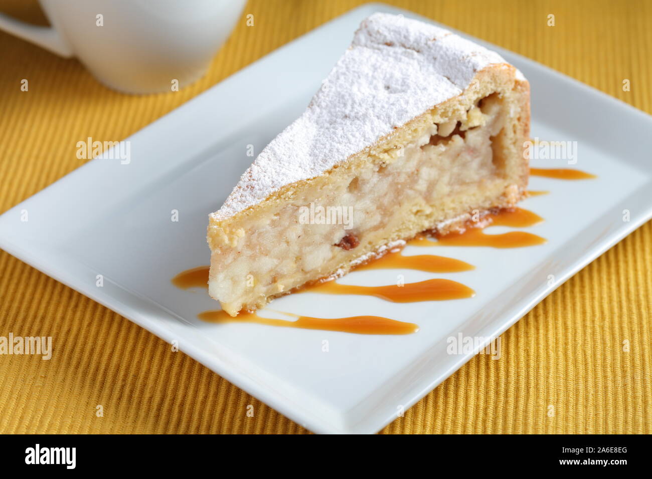 Slice of apple strudel topped with powdered sugar on a plate decorated with caramel sauce Stock Photo
