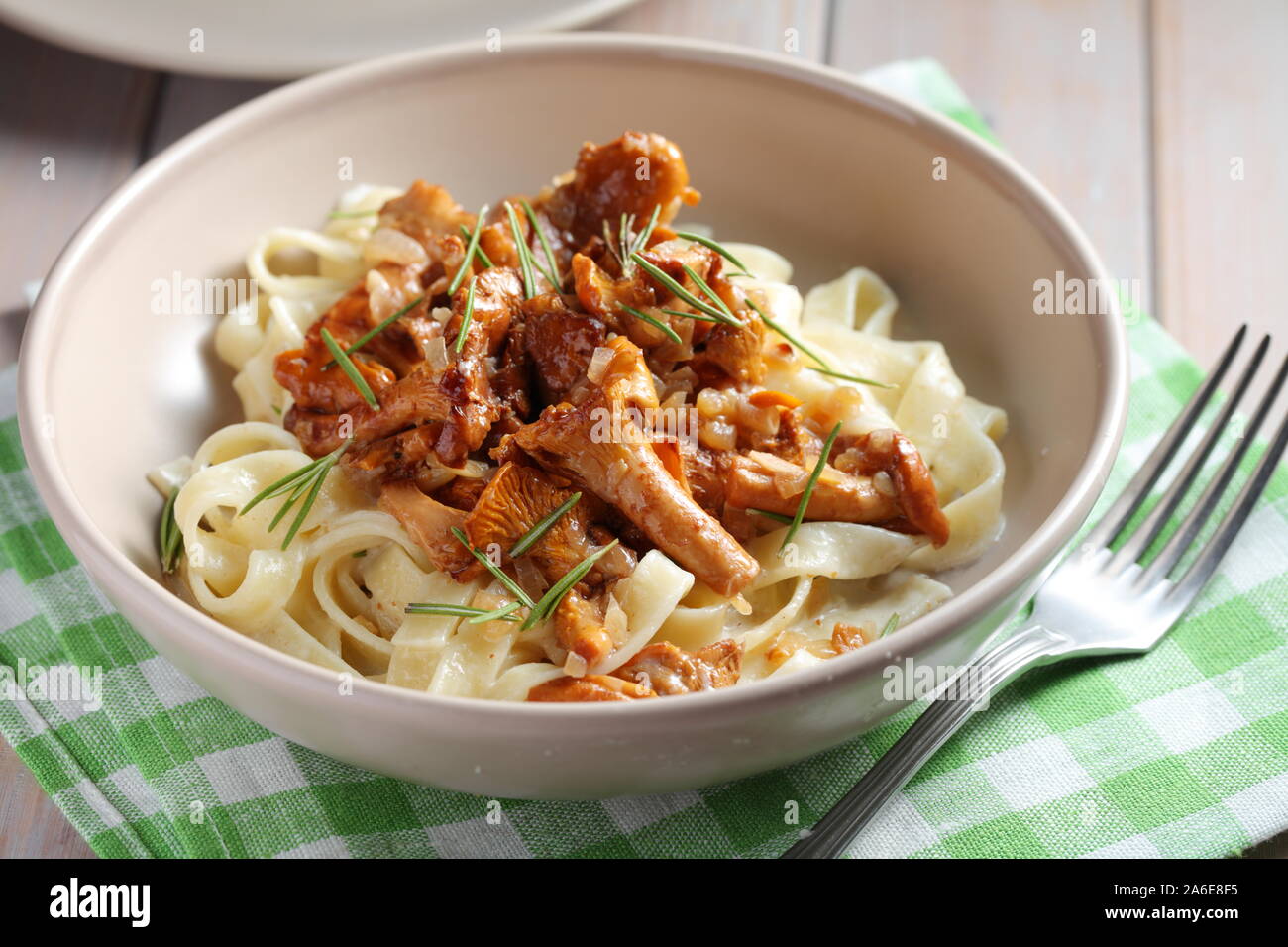 Fettuccine pasta with Chanterelle mushrooms and rosemary on a rustic table Stock Photo
