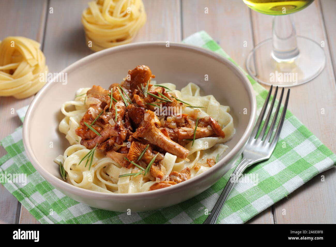Fettuccine pasta with Chanterelle mushrooms and rosemary on a rustic table Stock Photo
