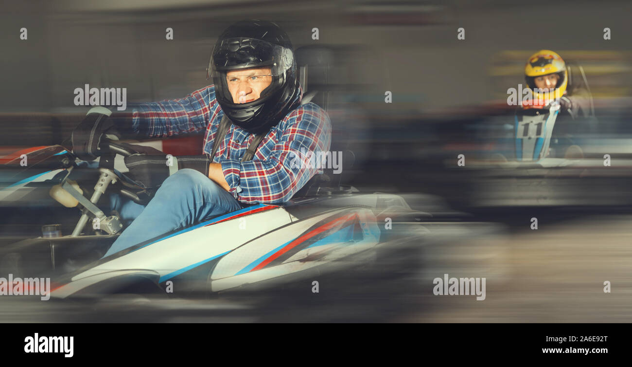 Portrait of cheerful positive smiling male racer in helmet driving kart ...