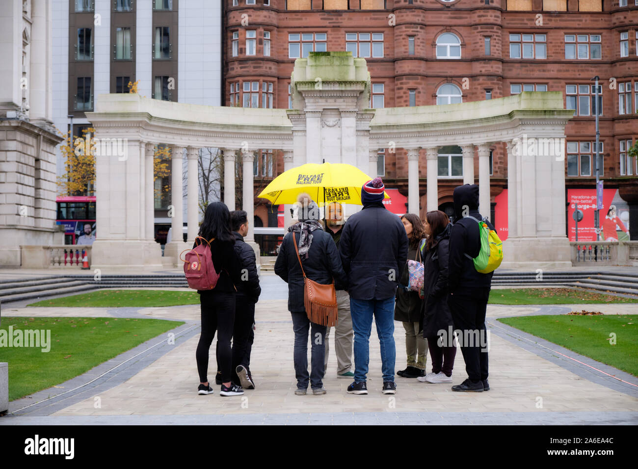 Tour guide on Free Walking Tour of Belfast with bright Yellow umbrella relating story at City Hall Stock Photo